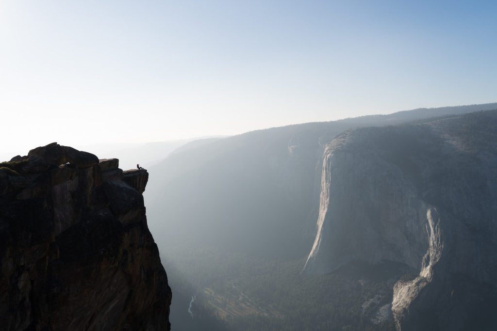 girl sitting on the edge of taft point in yosemite