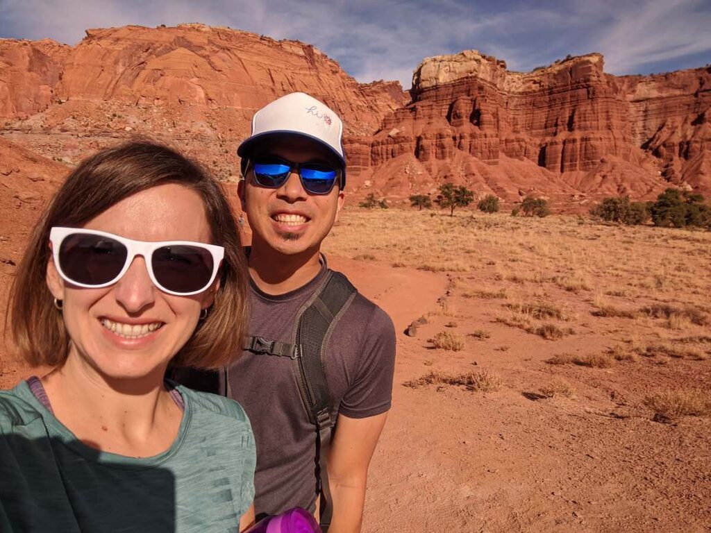 travelers taking a selfie in capitol reef utah with mesa in the background